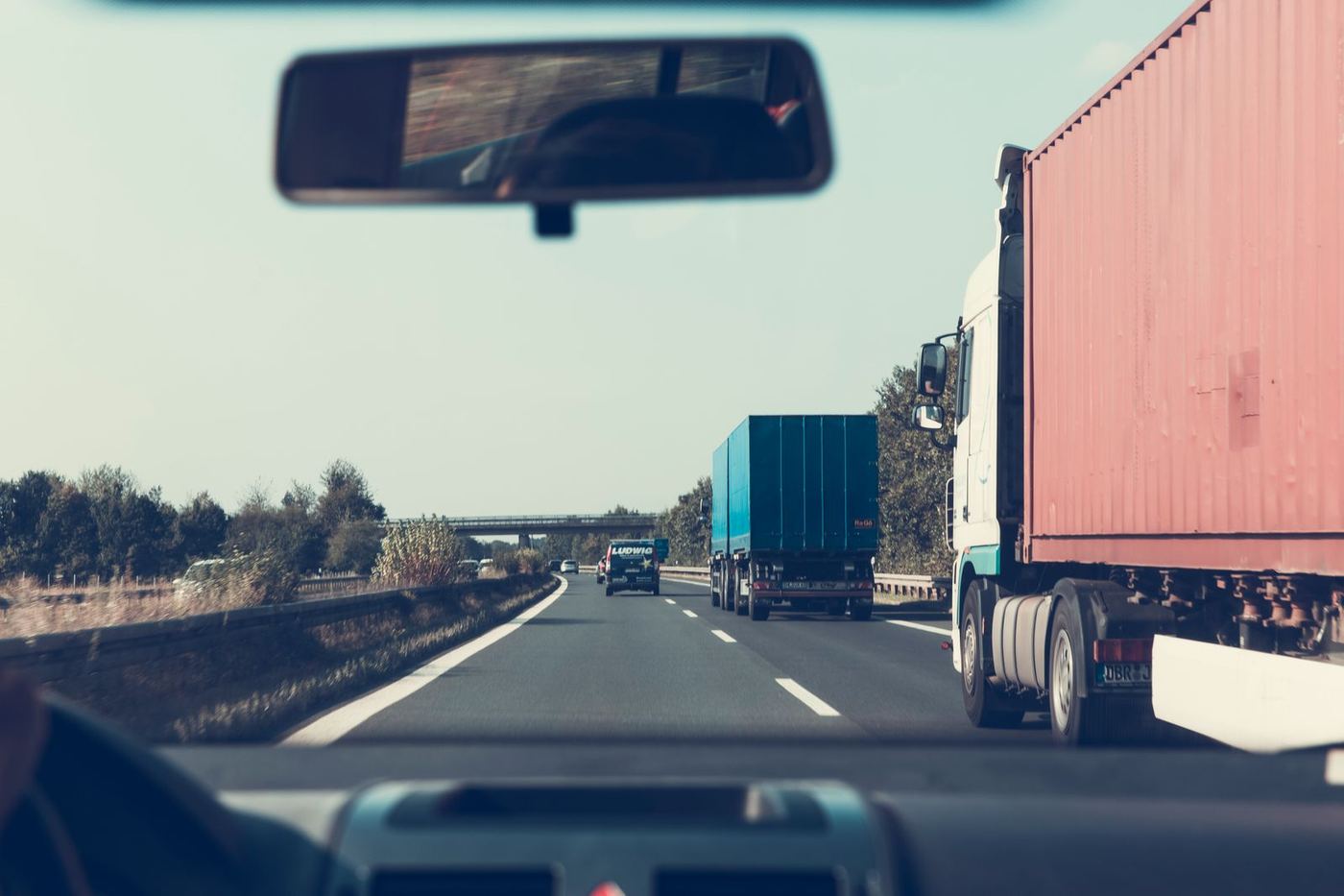 View from a cab following container trucks down the highway
